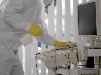 Medical Worker In Ppe Doing Sanitization Of Equipment In Hospital Room