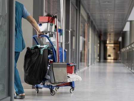 An Employee Pulls A Trolley For Cleaning Offices. Woman Cleaner Is Engaged In Work. Multi-purpose room cleaning