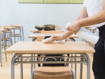 Teacher Disinfects Classroom Desk